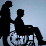 silhouette of someone pushing a person in a wheelchair