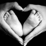 hands holding baby feet in heart